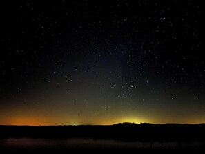 A night sky filled with stars over a landscape with a silhouette of a hill or mountain.