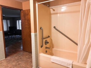 Baño con cabina de ducha, barras de apoyo y toallero.