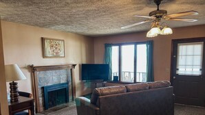 Una sala de estar con chimenea, sofá, televisor y ventilador de techo.