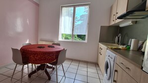 A compact kitchen with a table and chairs, a window, and a washing machine. - Maison Avec Jardin Clôt (Montélimar)