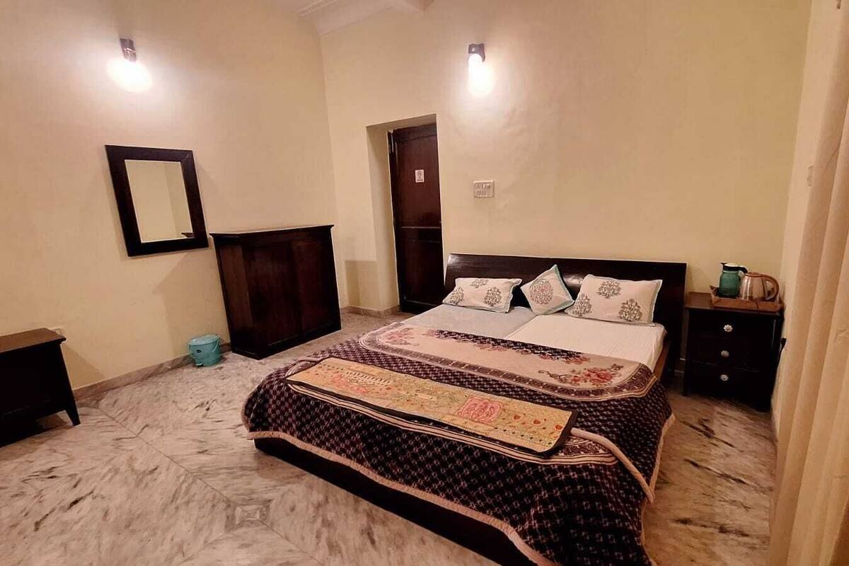 A bedroom with a large bed, a nightstand, a dresser, a mirror, and a door.