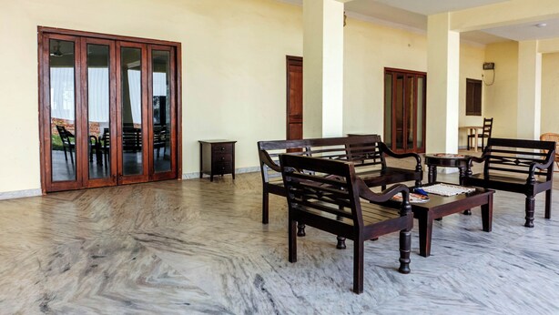 A spacious living area with a marble floor, wooden furniture, and large sliding glass doors leading to an outdoor area. - Urban Trippers Shamiyana Villa byArindam (Jaipur)