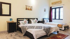 A hotel room with two beds, a nightstand, a mirror, an air conditioning unit, and a window with curtains. - Urban Trippers Shamiyana Villa byArindam (Jaipur)