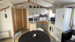 Una cocina compacta con microondas, estufa y lavabo, un comedor con mesa y sillas, y una sala de estar con sofá.