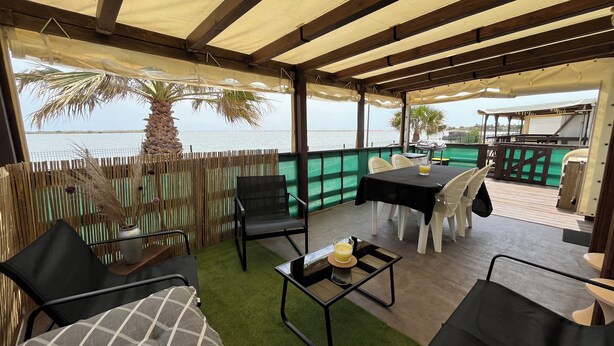 Un patio al aire libre con mesa y sillas, vista al mar y una palmera.
