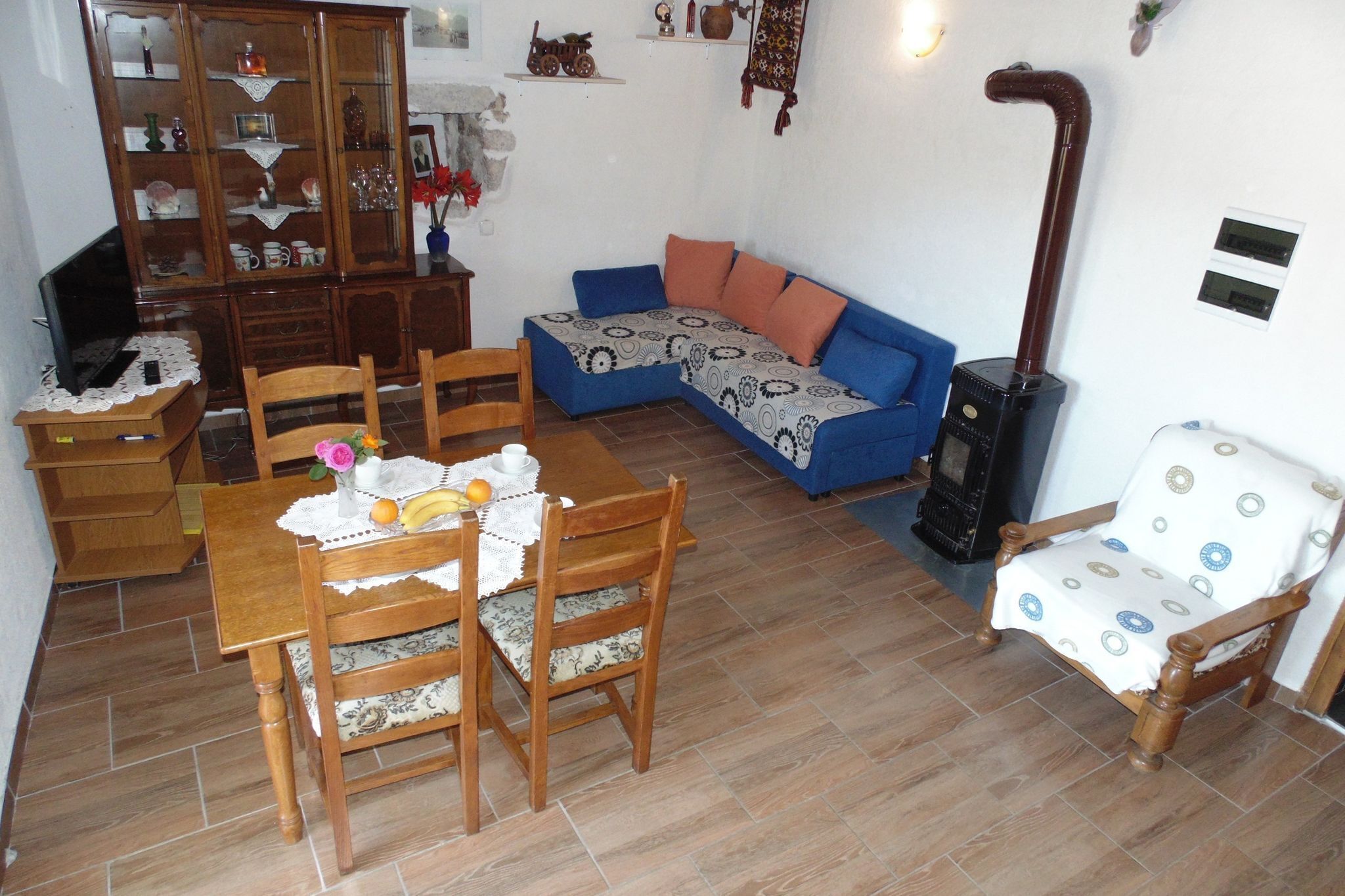 Ein gemütliches Wohnzimmer mit einem blauen Sofa, einem Holzesstisch, Stühlen, einem Schrank und einem Kamin.
