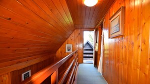 A wooden interior with a bench and a door leading to another room.