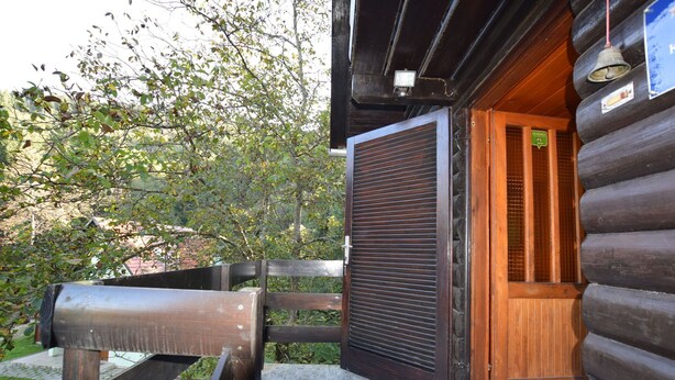 A wooden cabin with a sliding door, a metal bench, and a small porch area.