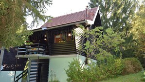 A log cabin with a balcony, surrounded by greenery.