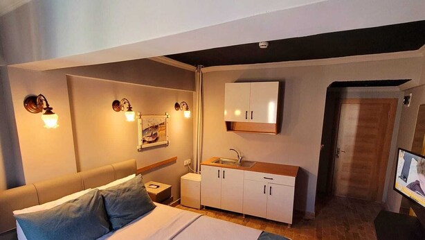 Une chambre à coucher comprenant un lit, des tables de chevet, une armoire, un miroir et un téléviseur.