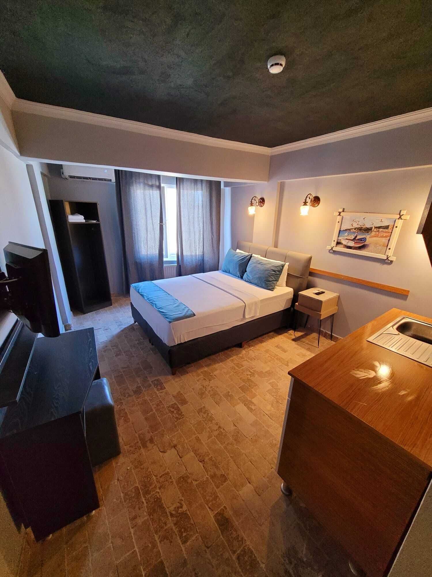 A modern hotel room with a large bed, a desk, a chair, and a small table.