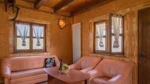 A cozy room with a wooden ceiling, two leather sofas, a small wooden table with fruit and drinks, and windows with curtains. - Holiday Home in Gorski Kotar with Pool (Brod Moravice)