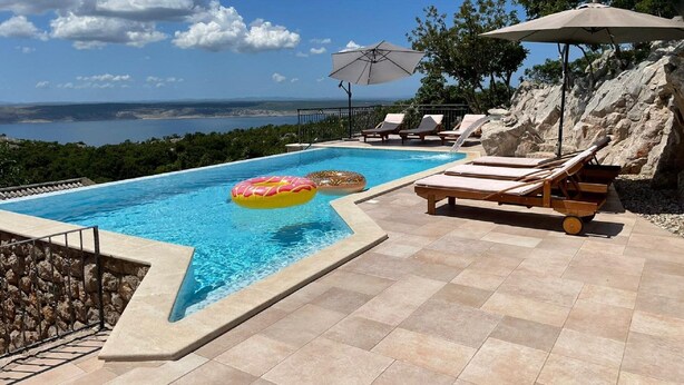 A swimming pool with a view of the sea, lounge chairs, and a rocky landscape. - Holiday Home in Starigrad with Sea View (Starigrad - Paklenica)