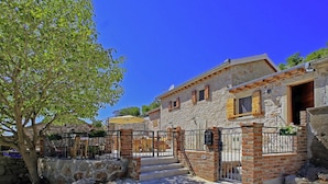 A stone building with a rustic exterior, a wooden door, and a small balcony. - Holiday Home in Starigrad with Sea View (Starigrad - Paklenica)