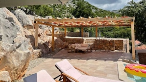An outdoor patio with a pergola, stone seating, and a pool area. - Holiday Home in Starigrad with Sea View (Starigrad - Paklenica)