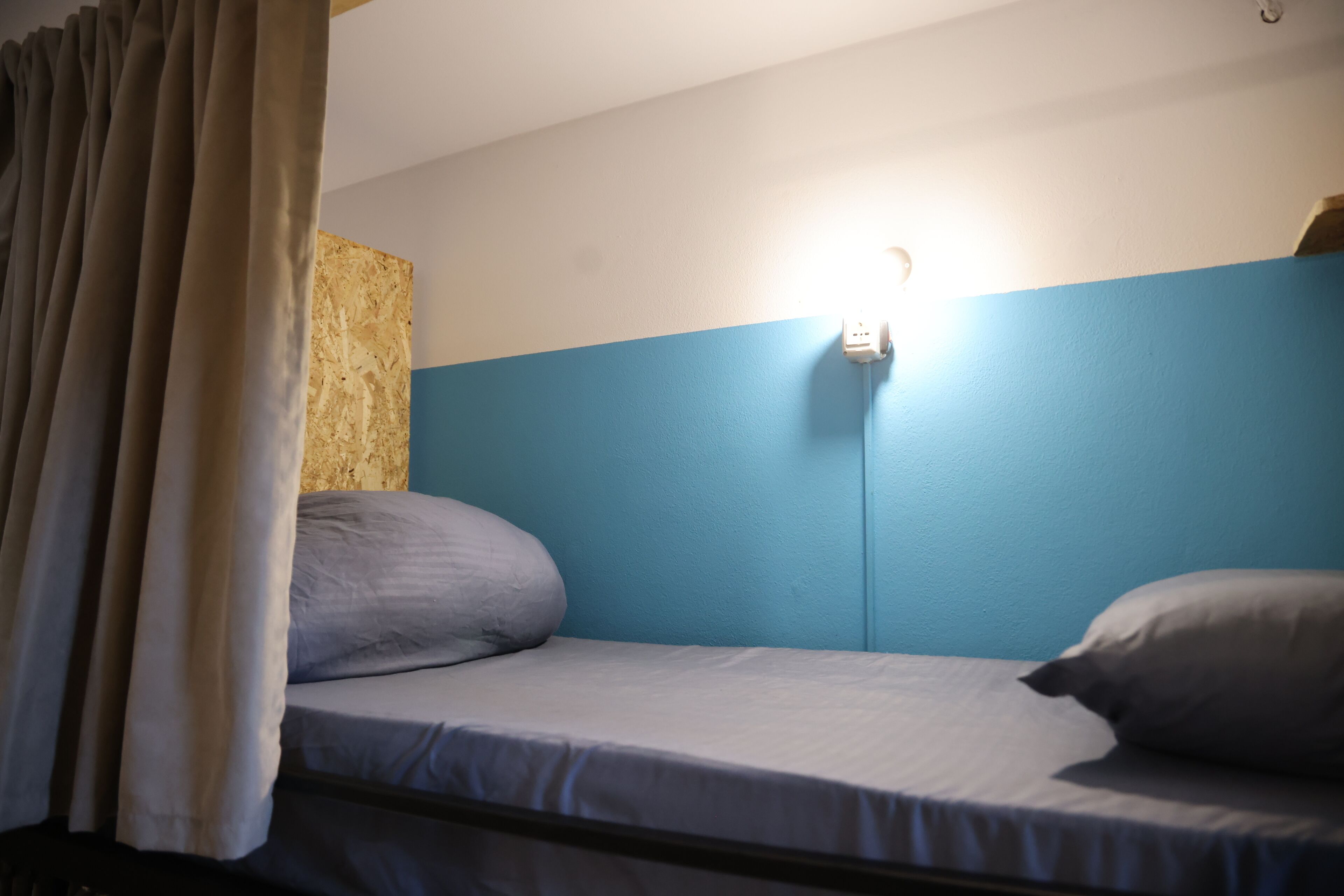 Un lit simple, avec un mur bleu clair et un panneau en bois sur le côté gauche.