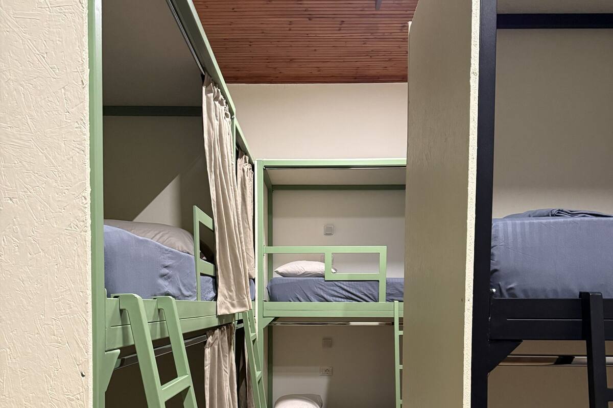 Une chambre de dortoir avec des lits superposés, un plancher en bois et une échelle.