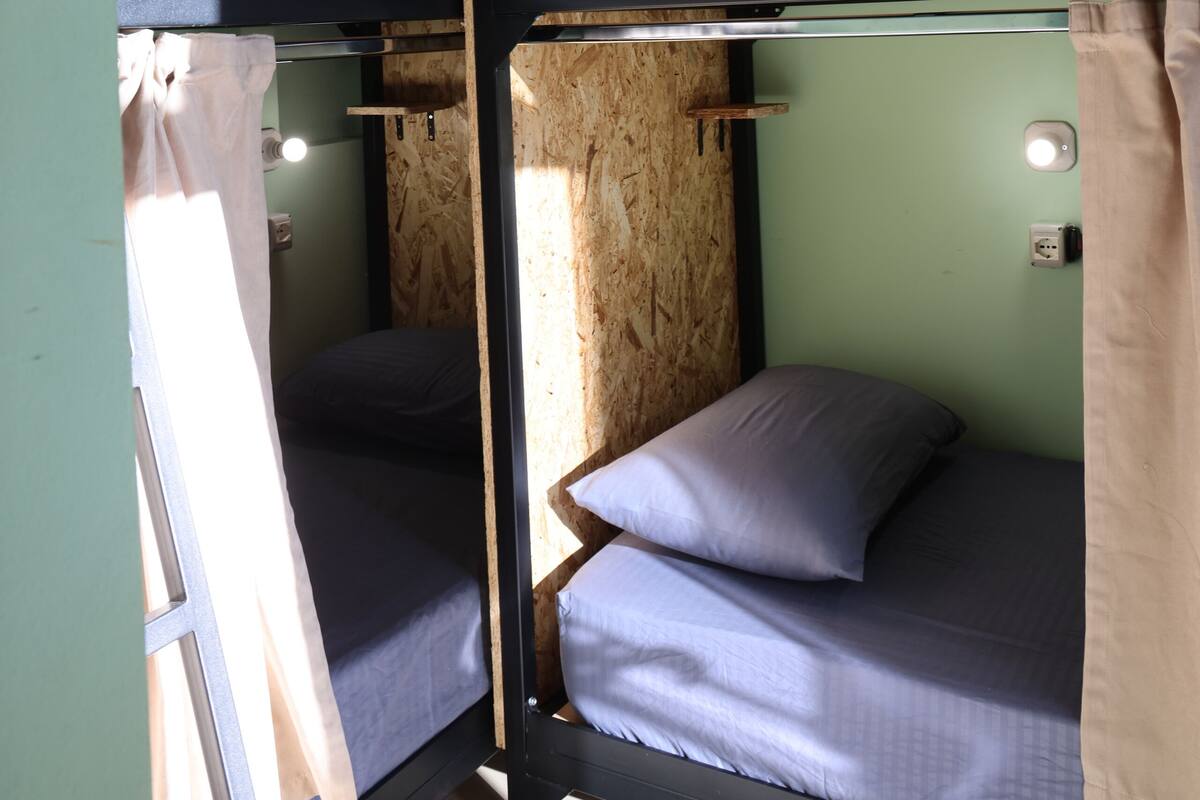 Une chambre avec un lit superposé à deux niveaux, des murs en bois et un mur d’accent vert.