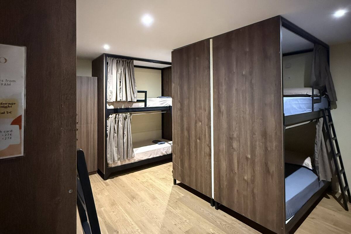 Une petite chambre avec un lit superposé et une armoire.