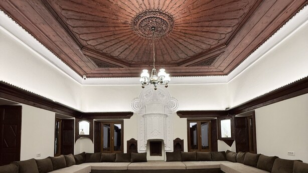 A spacious room with a large L-shaped sofa, a central coffee table, and a chandelier. - Shkodra Hostel (Shkodër)
