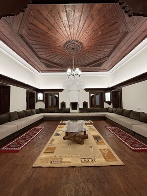 A spacious room with a large L-shaped sofa, a central coffee table, and a chandelier. - Shkodra Hostel (Shkodër)