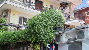A multi-story building with balconies adorned with flowers, a sign indicating amenities like Wi-Fi and air conditioning, and a gated entrance. - Shkodra Hostel (Shkodër)