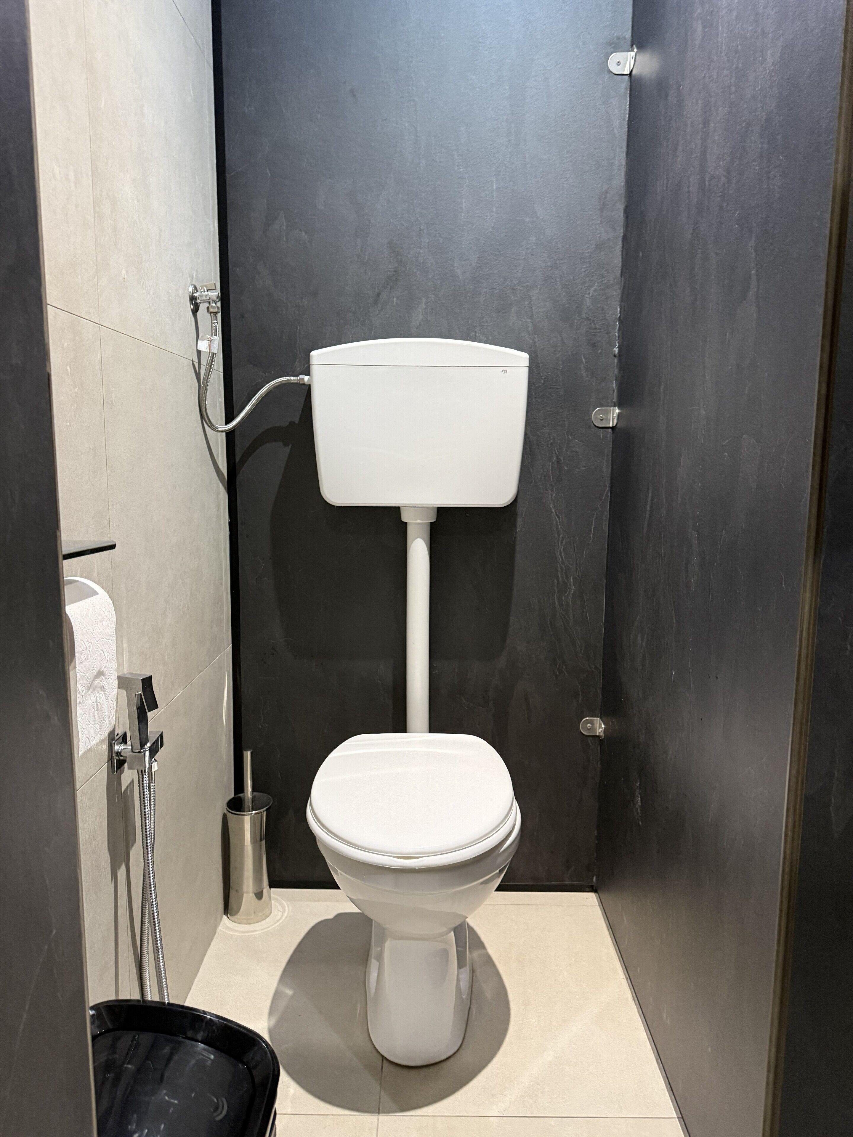 Une salle de bain moderne avec des toilettes blanches, une douche et un porte-rouleau de papier toilette.