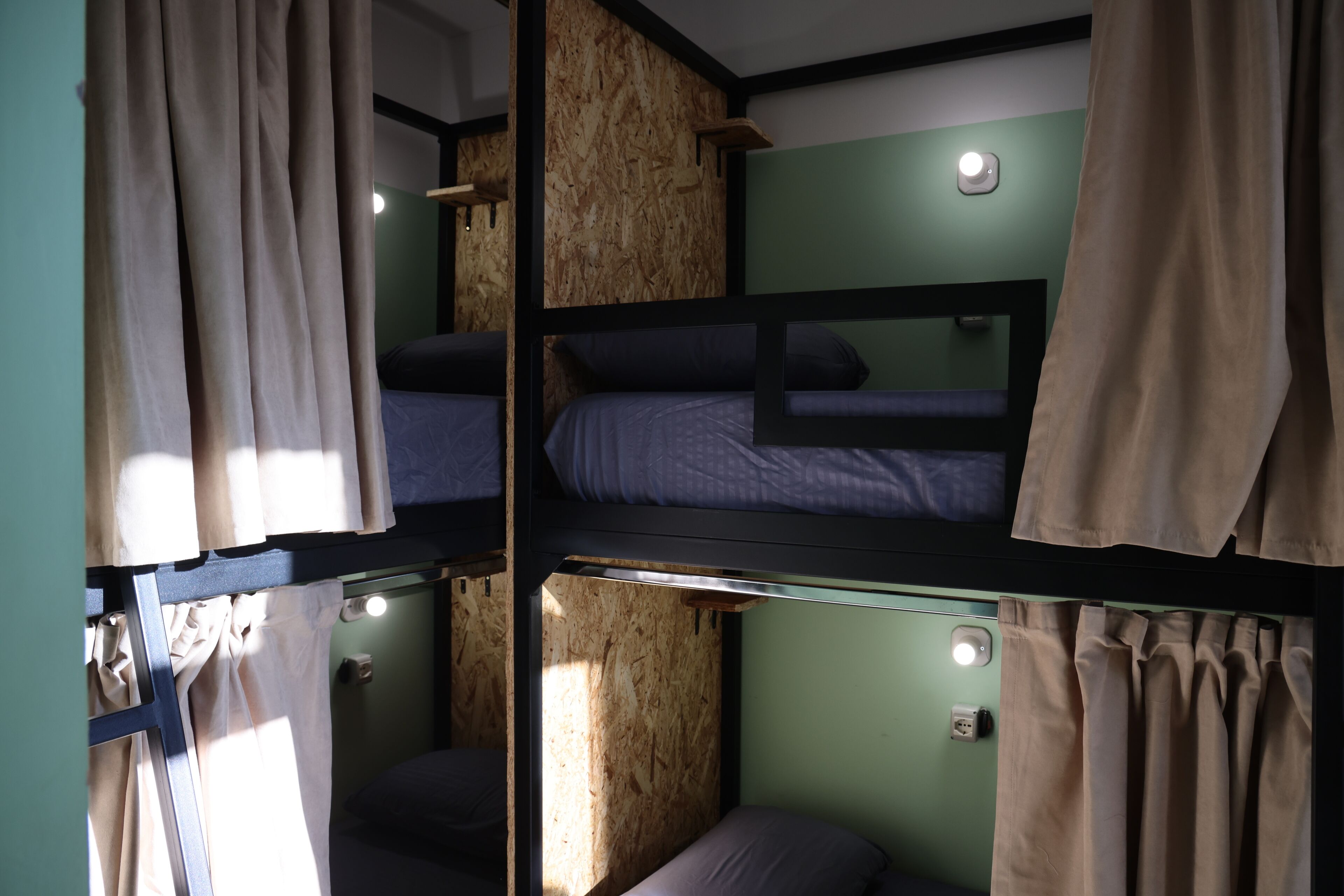 Une chambre avec un lit superposé, un mur vert, un lambris en bois et un luminaire.