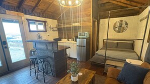 A rustic cabin with a wooden interior, a kitchenette, a bed, and a dining area.