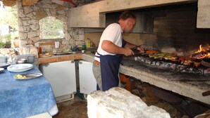 Una cocina de paredes de piedra con horno de piedra, un lavabo y un refrigerador pequeño.