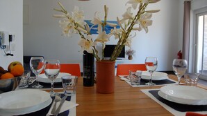 Una mesa de comedor dispuesta con platos, vasos y un florero con flores blancas.