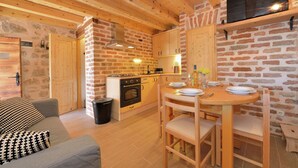 A cozy kitchen with wooden beams, a brick wall, and a dining area with a table set for two. - Seaside Retreat in Marina di Grosseto (Starigrad Paklenica)