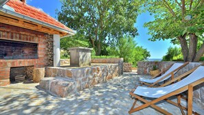 A stone patio with lounge chairs, a brick fireplace, and a view of the sea. - Seaside Retreat in Marina di Grosseto (Starigrad Paklenica)