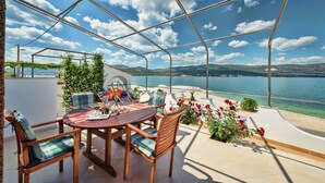 Une terrasse avec une table et des chaises, donnant sur un plan d’eau et des collines.