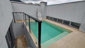 A rooftop swimming pool with a glass railing, a white chair, and a staircase leading down. - Saint Sebastian ap103-stúdio  (Jaragua do Sul)