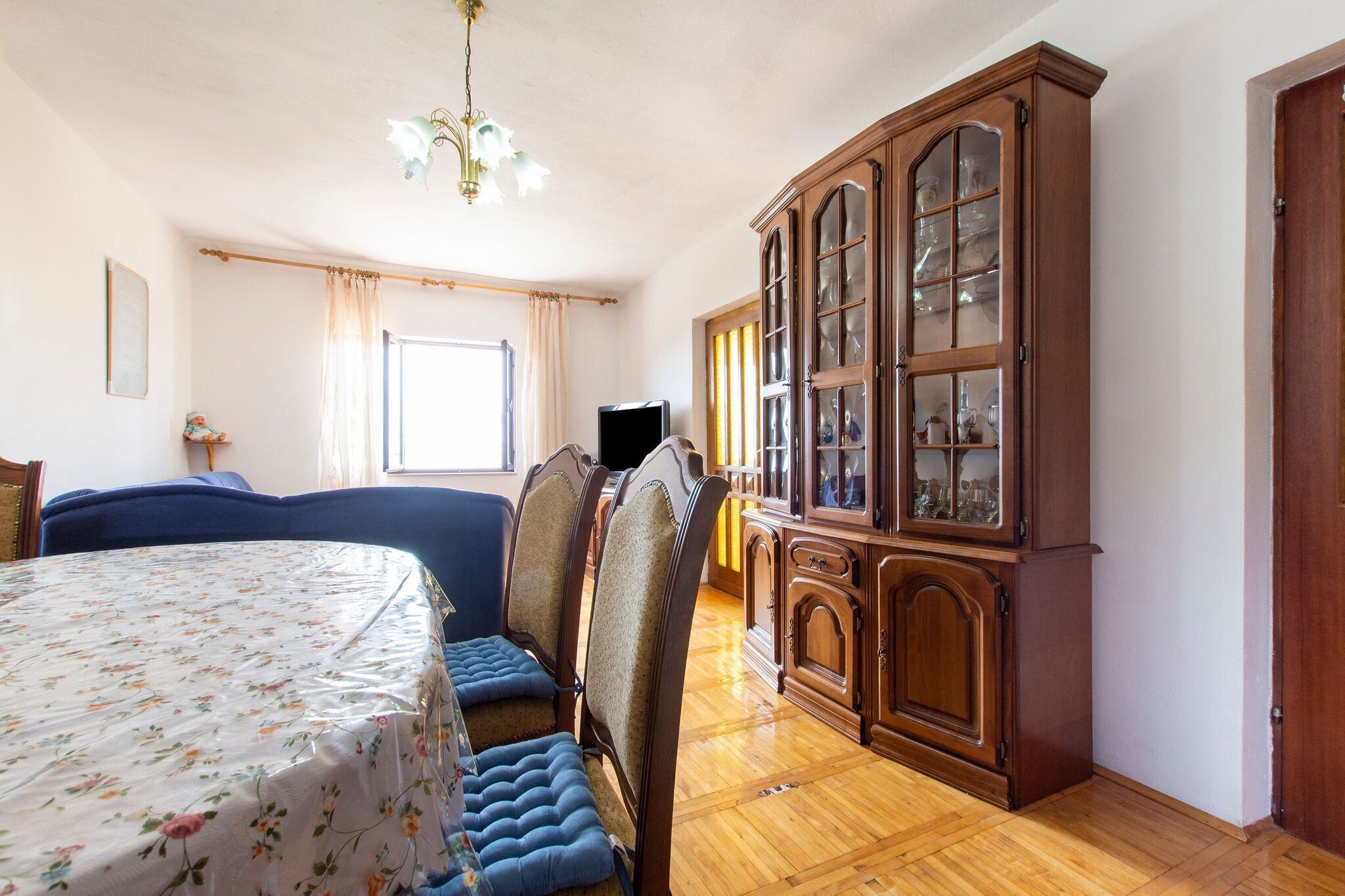 A room with a bed, a wooden cabinet, a television, and a window with curtains.