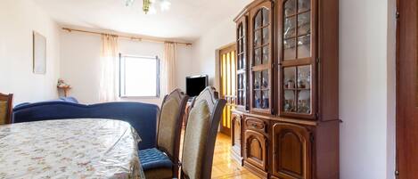 A room with a bed, a wooden cabinet, a television, and a window with curtains.