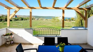 A covered patio with a view of a green landscape and a body of water. - Apartment in Ljubac with Barbecue (Ljubac)