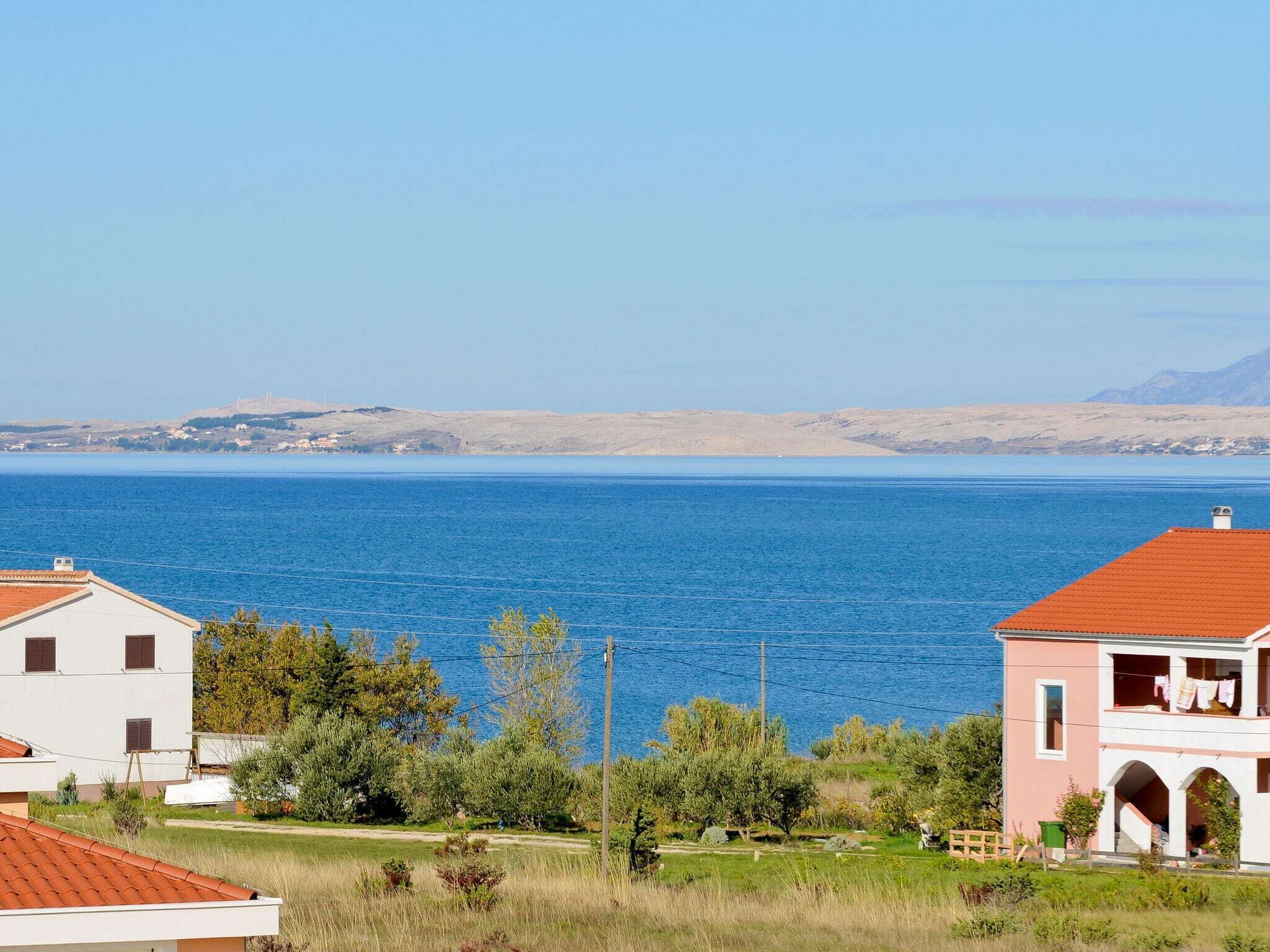 Une vue sur la côte, avec une étendue d’eau importante, une plage de sable et quelques bâtiments aux toits rouges.