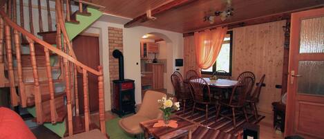 A wooden interior with a spiral staircase, a dining area with chairs and a table, and a fireplace.