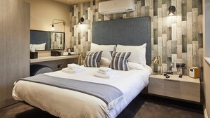 Une chambre d’hôtel moderne, dotée d’un grand lit, d’une table de chevet, d’un miroir et d’un climatiseur fixé au mur.