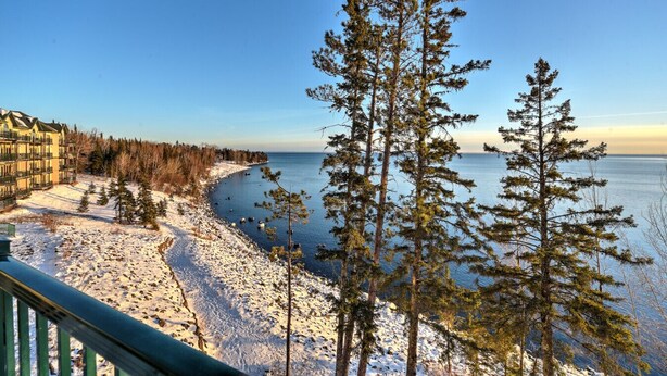 Una spiaggia innevata con vista sul mare e un edificio con numerosi balconi.