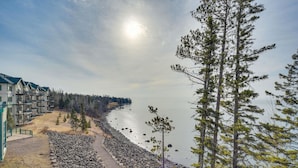 A coastal view with a rocky shoreline, a row of multi-story buildings, and a clear sky. - Two Harbors Superior Lakefront 3BR Corner | Pool | Hot Tub | Sauna | EV Charger (Two Harbors)