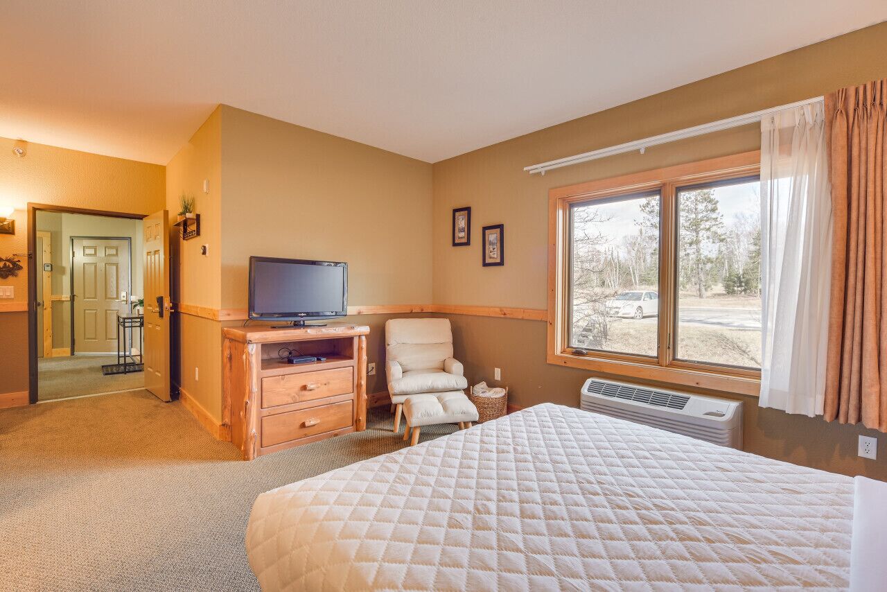 A hotel room with a bed, a TV, a chair, a desk, and a window with a view of the outside.