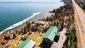 An aerial view of a coastal property with multiple buildings, a road, and a beach.