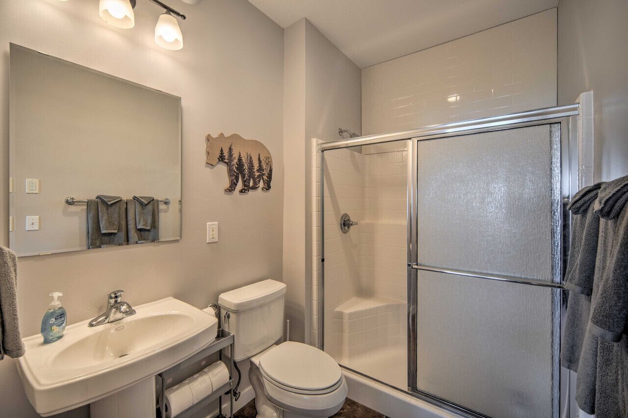 Une salle de bain avec un lavabo blanc, un miroir, des toilettes et une douche à parois de verre.