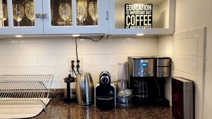 A kitchen with a coffee maker, kettle, and toaster. There is a sign above the counter that reads "EDUCATION IS IMPORTANT BUT COFFEE IS IMPORTANTTANIER." - Wells Whole House (Bridgeport)