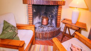 Un salon chaleureux avec une cheminée en briques, un canapé en bois, une petite table et une lampe.