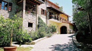 Un bâtiment en pierre doté d’un balcon, d’une porte et d’un chemin menant à l’entrée.