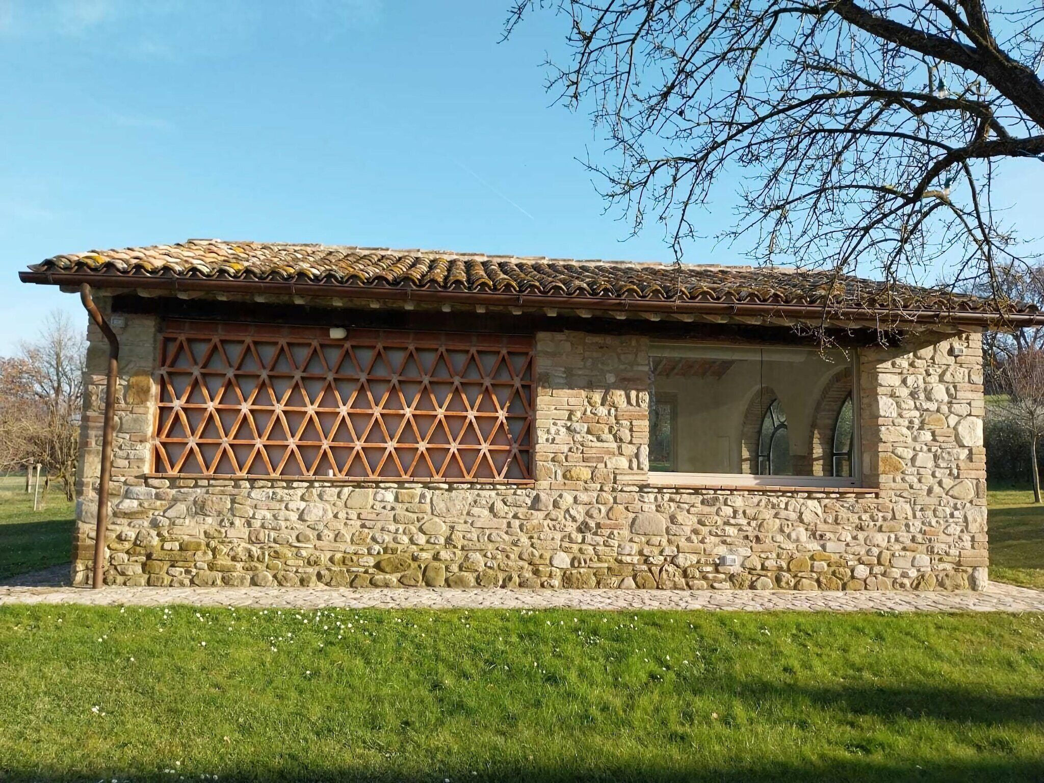 A stone building with a tiled roof, a lattice window, and a stone wall.